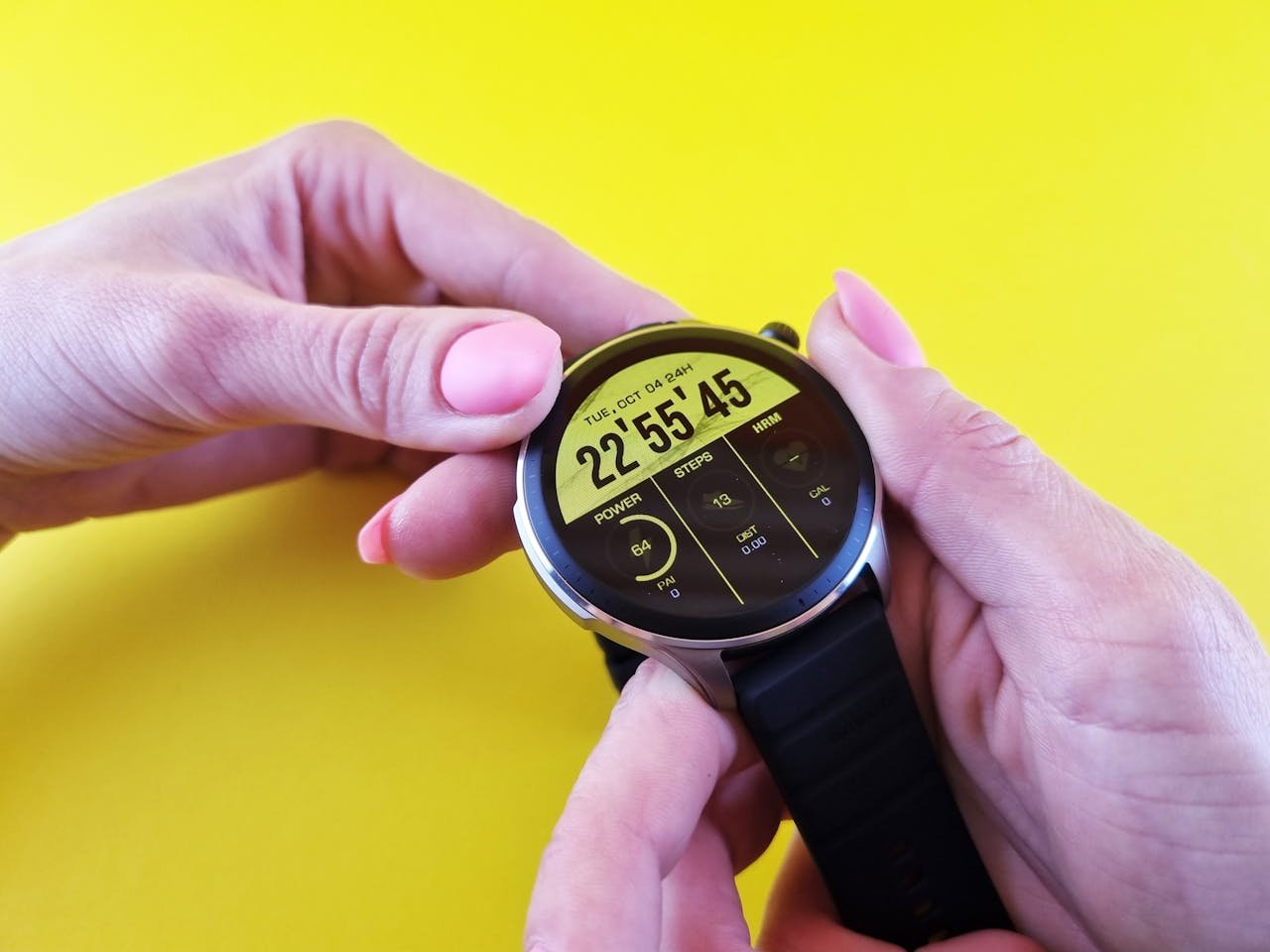 Services-02 Close-up of hands holding a sleek smartwatch, highlighting technology against a bright yellow background.
